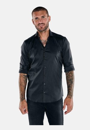 Schwarzes Button-up-Hemd mit hochgerollten Ärmeln, aus glattem Stoff. Verfügt über eine taillierte Passform und fünf Knöpfe vorne.