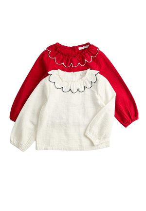 Rød langærmet bluse med flæset halsudskæring og hvid langærmet bluse under med bølget flæsekant, begge i tekstureret stof.