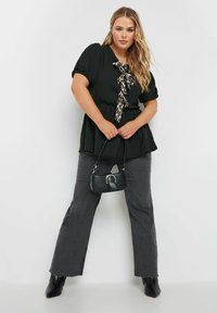 Blusa nera con maniche a sbuffo, con dettagli a cravatta in stampa leopardata. Abbinata a jeans grigi a vita alta e stivaletti neri.