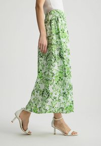 Falda larga, verde y blanca con un diseño floral, hecha de una tela suave. Presenta una cintura fruncida y una silueta fluida.