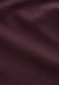 Textúrovaná tkanina v hlbokej burgundskej farbe, s tkaným vzorom a mäkkým, mierne vyvýšeným povrchom a jemným leskom.