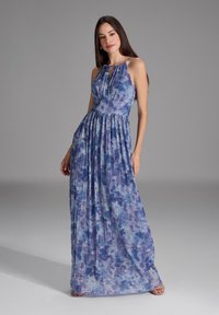 Vestido maxi con un patrón tie-dye que presenta tonos de azul y púrpura. Textura plisada con un corsé ajustado y una falda fluida. Tirantes finos.