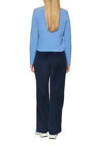 Blauw langemouwtop gecombineerd met marineblauwe corduroy wijde broek, met een zachte textuur en een relaxte pasvorm, aangevuld met witte sneakers.