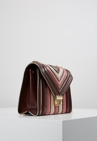 Bolso de mano con patrón de chevron en cuero burdeos, rosa y beige, que presenta herrajes dorados y un diseño de solapa estructurada.