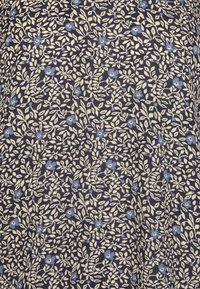 Motif dense de petites feuilles crème et de fleurs bleues éparses sur un fond de tissu bleu marine foncé.