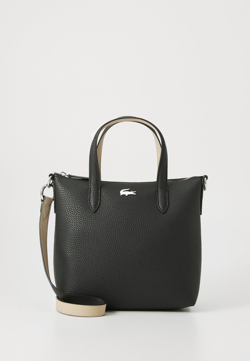 Black textured leather handbag with short handles and a detachable beige strap, featuring a silver logo on the front.