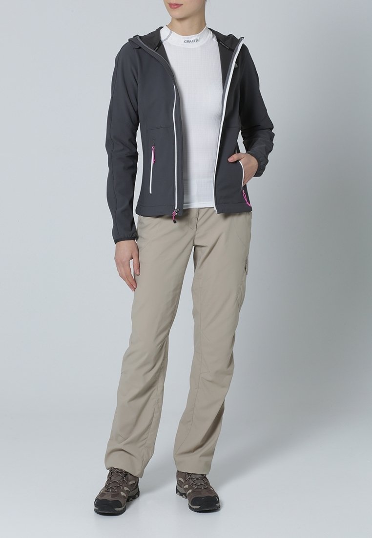 Grauer Kapuzenjacke mit weißen Reißverschlüssen und pinken Akzenten, über einem eng anliegenden weißen Oberteil und beigen Cargo-Hosen getragen. Braune Wanderschuhe runden den Look ab.