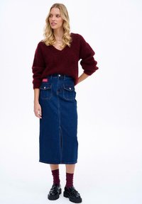 Burgundská nadýchaná mikina s výstrihom do V, skombinovaná s dlhou denimovou sukňou s predným rozparkom a dvoma zadnými vreckami. Čierne platformové topánky, marhuľové ponožky.