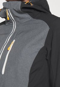 Veste pour homme présentant un tissu gris à finition texturée avec des accents noirs, un col montant, et des tirettes de fermeture éclair orange pour un détail supplémentaire.