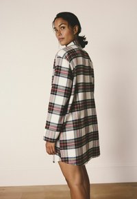 Kárované šaty ve smetanové, červené, námořnické a zelené barvě, dlouhé rukávy, límec, boční rozparky, mírně oversized střih.