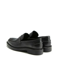 Mocassins en cuir noir avec une finition lisse, un petit talon empilé et des côtés découpés ; présentent un motif de couture subtil le long de la tige.