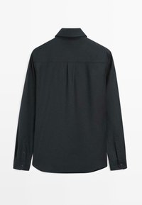 Camicia nera a maniche lunghe con colletto, dettaglio della piega posteriore, orlo arrotondato e polsini con bottone. Realizzata in un tessuto liscio con finitura opaca.