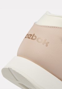 Helle rosa Leder-Sneaker mit weißen Akzenten, ausgestattet mit einer strukturierten Oberfläche und geprägtem Reebok-Logo auf der Ferse. Runde Zehenpartie und Gummisohle.