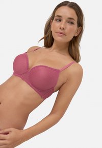 Sostén acolchado rosa con puntas de encaje y textura de lunares. Cuenta con tirantes ajustables y un diseño con aros estructurados.