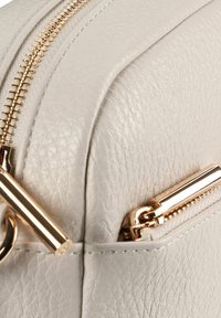 Borsa in pelle grigio chiaro con cerniere e accessori in tono oro, superficie strutturata e design elegante. Include un dettaglio zip prominente.