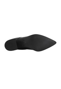 Suola di una scarpa da uomo nera con punta affusolata, con tacco texture e parte anteriore liscia, su sfondo bianco.