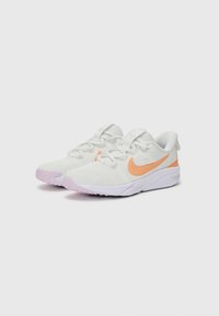 Baskets blanches en tissu texturé, avec le Swoosh orange de Nike, des accents violets et une semelle blanche avec un motif de traction.