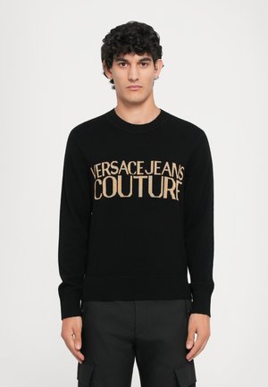 Sort strikket sweater med ribbet rund hals. Guld broderet "VERSACEJEANS COUTURE" logo, der er fremtrædende placeret på forsiden. Tætsiddende design.