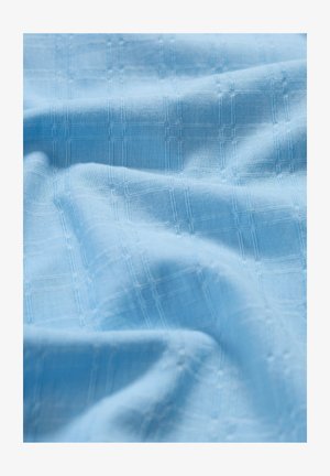 Lyseblå vævet stof med et tekstureret gittermønster, blødt fald og subtil glans. Glat tekstur og let sammensætning.