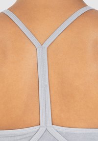 Lichtgrijze sportbh met een smal racerback ontwerp. Glad, rekbaar materiaal met platte naden en een schone afwerking aan de randen.