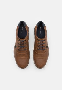 Chaussures en cuir marron avec une finition texturée, avec des accents navy, un design à lacets et une semelle contrastée. Vue de dessus.