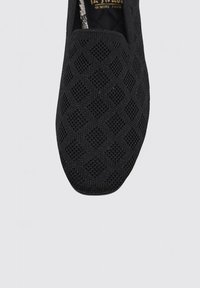 Zapato negro sin cordones con parte superior de punto texturizado que presenta un patrón de diamantes. Punta redondeada y construcción flexible. Suela duradera. Plantilla de espuma con memoria.