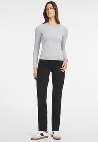 Pilkas ilgas rankovės marškinėliai derinami su juodomis slim-fit džinsais ir baltais sportbačiais su juodais akcentais. Paprastas dizainas su tamprių audinių.