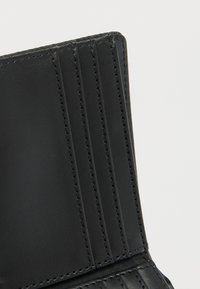 Μαύρο δερμάτινο πορτοφόλι με πολλαπλές θήκες για κάρτες, ομαλή υφή και ενισχυμένα ραφές. Συμπαγές σχέδιο χωρίς εμφανείς μεταλλικές λεπτομέρειες.