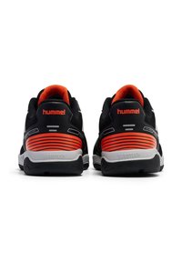 Scarpe da ginnastica nere con accenti arancioni, tomaia in mesh per traspirabilità, suola in gomma e un distintivo design a strisce orizzontali sul tallone.
