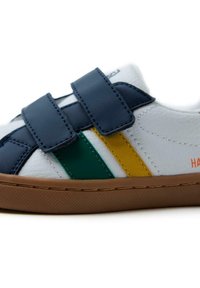 Baskets blanches avec des scratchs bleu marine, des rayures vertes et jaunes, et une semelle en caoutchouc marron. Le texte "HARDY" est sur le côté. Texture douce.