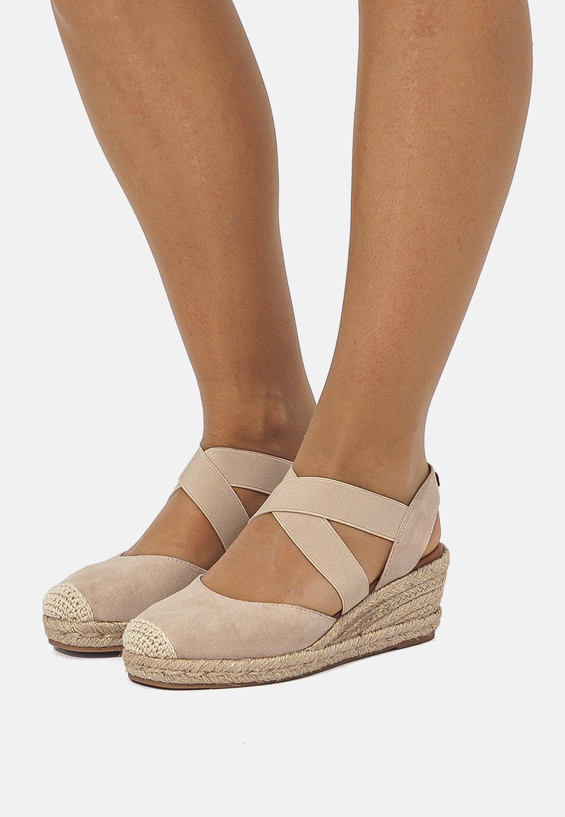 Sandalias de cuña de ante beige con tiras cruzadas, suela de yute texturizada y puntera redondeada con un detalle tejido en la parte delantera.