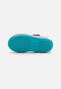 Obuv s tyrkysovou podrážkou, růžovými akcenty a texturovaným vzorem na povrchu. Obsahuje suchý zip přes vrch pro nastavení.