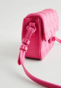 Fuchsia kviltad syntetisk handväska med en platt form, rundade kanter och en justerbar rem. Har en knappstängning och en mjuk yta.