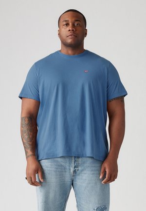 Tricou din bumbac albastru, cu guler rotund și mâneci scurte, decorat cu un mic logo roșu Levi's pe piept, asortat cu blugi albaștri deschisi.