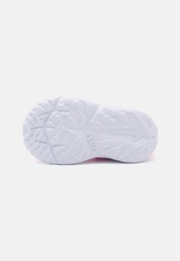 Suola di sneaker in gomma bianca con un motivo di trazione testurizzato; presenta un logo circolare e un leggero gradiente di colore verso il tallone.