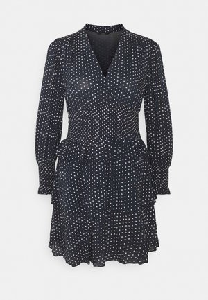 Robe à manches longues bleu marine avec des pois rose clair, encolure en V, taille cintrée et jupe à volants superposés.