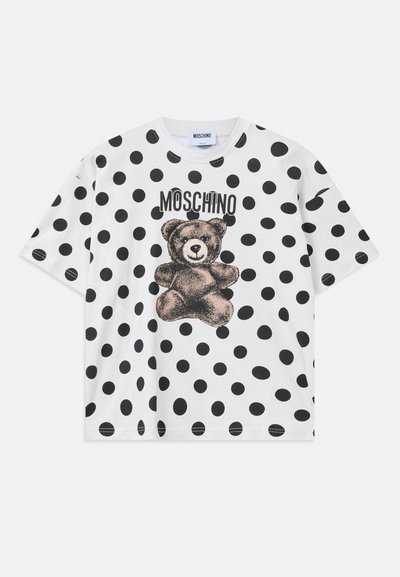 White cotton t-shirt featuring a black polka dot pattern, a bear graphic, and "Moschino" text in black above the design. Short sleeves.