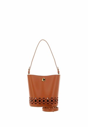 Bolso tipo cubo de piel marrón con un diseño floral recortado cerca de la base, un cierre circular dorado y una correa de hombro ajustable al lado.