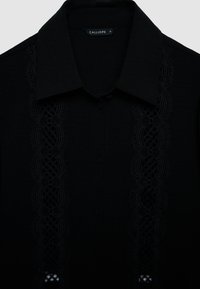 Schwarzes Hemd mit Knopfleiste und strukturiertem Spitzenbesatz entlang der Vorderseite, mit klassischem Kragen und glattem Stoffabschluss.