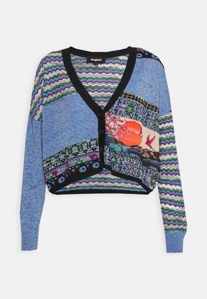 Cardigan court multicolore bleu, avec un col en V noir, une fermeture à boutons, et divers motifs incluant des designs floraux et géométriques.
