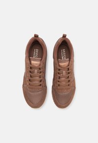 Brown textile sneakers with a mesh design, round toe, and laces. Features a logo on the tongue and a rubber sole for traction.