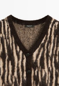 Cardigan duveteux à col en V avec des rayures abstraites verticales marron foncé et beige et deux boutons noirs, étiquette indiquant Massimo Dutti.