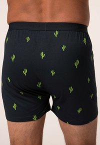 Boxer neri con piccoli stampi di cactus verdi. L'elastico in vita presenta la scritta "JP1880." Materiale in cotone con una texture liscia.