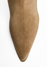 Brun mockaskinnsko med spetsig tå som har en slät yta, minimalistisk design och en smal silhuett med synliga sömdetaljer.