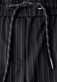 Black striped fabric features with a textured surface, drawstring closure in dark gray, and silver accents for adjustability.