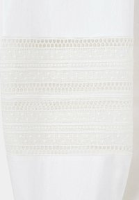 Tissu blanc avec des bandes horizontales de dentelle blanche raffinée et des motifs en résille créant un design décoratif texturé.