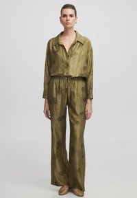 Ensemble deux pièces vert olive en tissu léger. La chemise présente un col et des boutons, tandis que le pantalon a une taille élastique et des motifs floraux.
