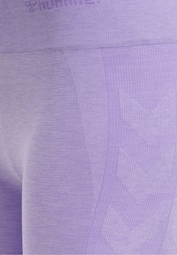 Fioletowe legginsy sportowe z prążkowaną teksturą i wzorem w zygzak po bokach. Materiał jest gładki i elastyczny, co zapewnia komfort.