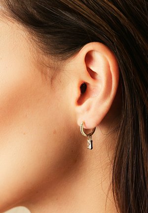 Guldørering i hoop stil med en struktureret overflade, prydet med en lille klar perle charm hængende fra den. Cirkulært design, kompakt størrelse.