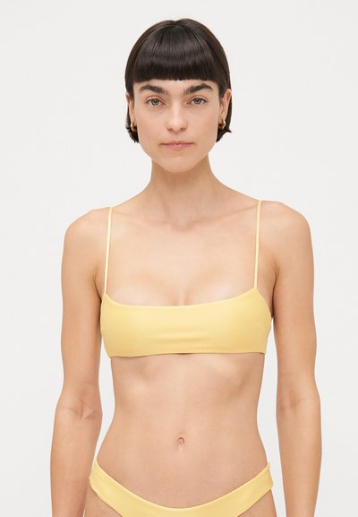 Top de bikini amarillo con una textura suave, corte rectangular y tirantes finos, emparejado con una parte de abajo de bikini a juego.